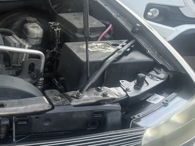 A car battery sitting in the corner of an engine bay