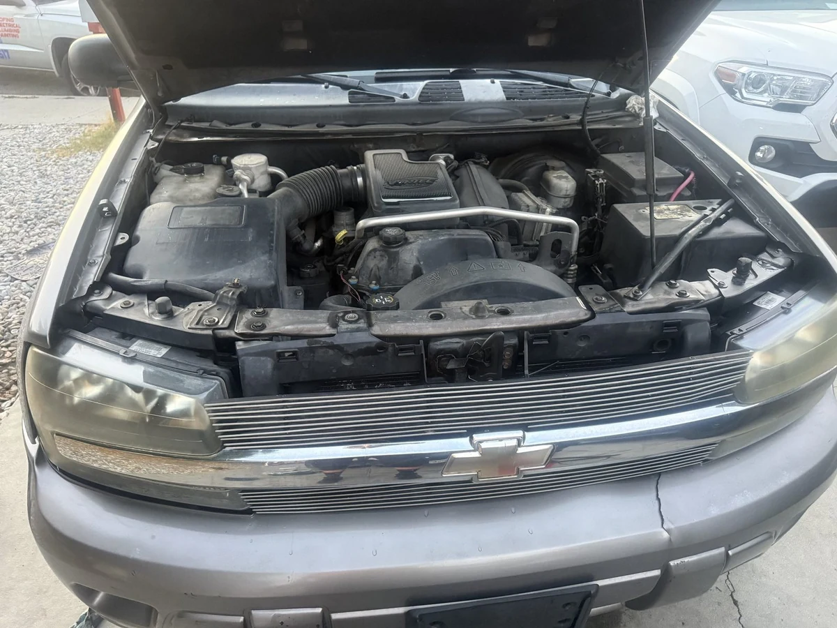 The open engine bay of a Chevy Trailblazer with the hood propped up